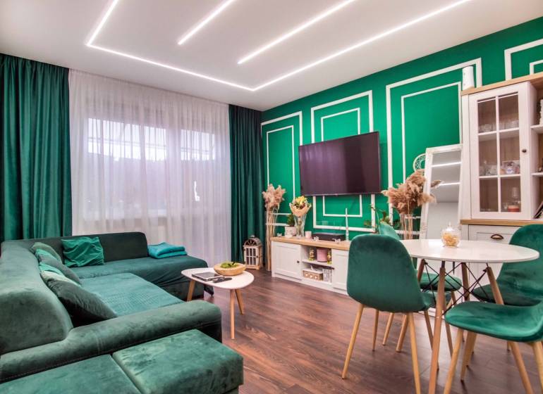 Living room in a two-room apartment with a comfortable sofa and a wooden-patterned floor.