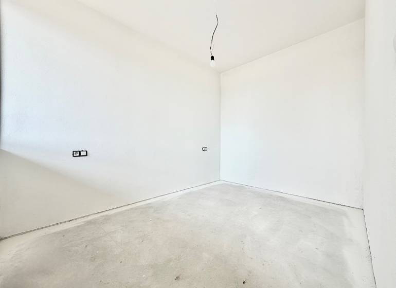 An empty room with white walls and a floor with wood decor in a studio apartment.