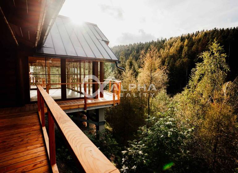 The family house in Hnilčík is surrounded by forest and has a wooden terrace with a view.