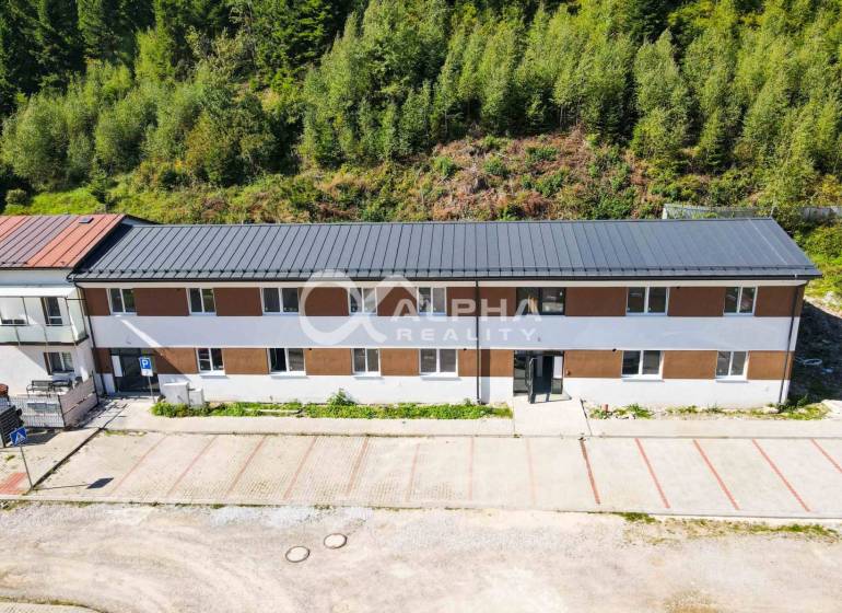A building in Spišská Nová Ves with a parking lot, surrounded by a green forest.