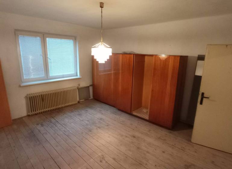 A room with wooden decor, a wardrobe, and a window in a family house.