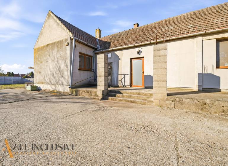 Exterior of commercial premises in Jelka with a concrete yard and a sloped roof.