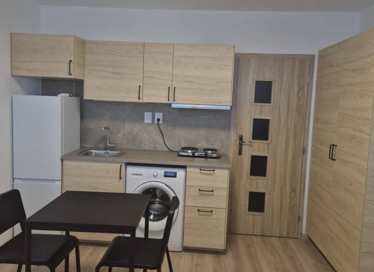 Kitchen unit in a studio apartment with a dining table and a floor with a wooden decor.