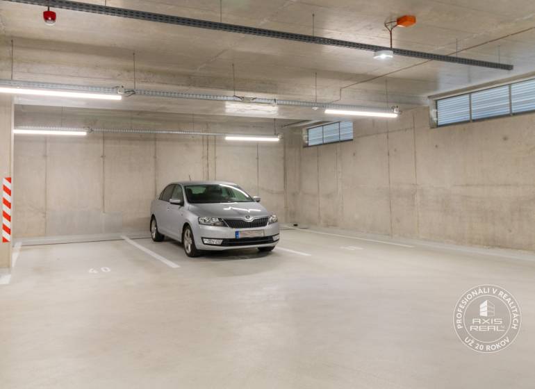Underground parking lot with a car, concrete walls, and lighting in the garages.