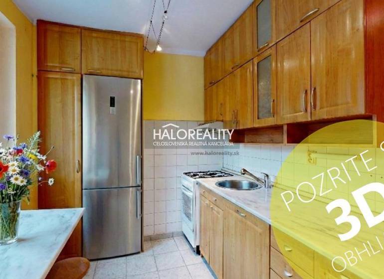 A kitchen with a light-colored unit and flowers, in a 2-room apartment, with a window and appliances.