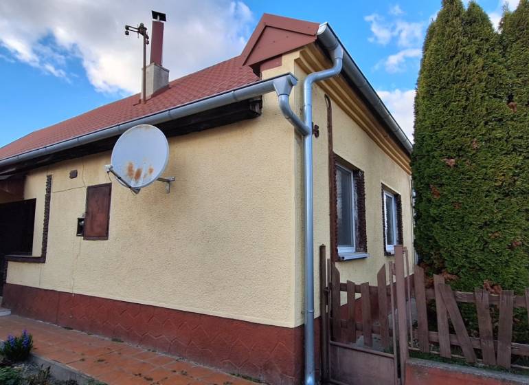 A family house in Holiare surrounded by greenery, with a satellite dish on the facade.
