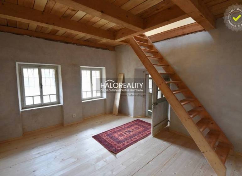 Interior of a cabin with a wooden staircase, a floor with a wooden decor, and a carpet.