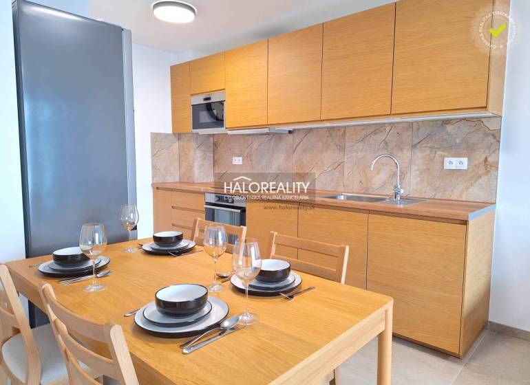 A kitchen in a 2-room apartment with wooden decor, built-in appliances, and marble cladding.
