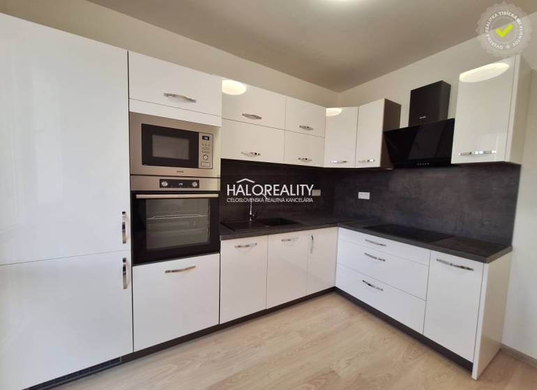 A kitchen with white cabinets, black appliances, and a wood-patterned floor in a three-room apartment.