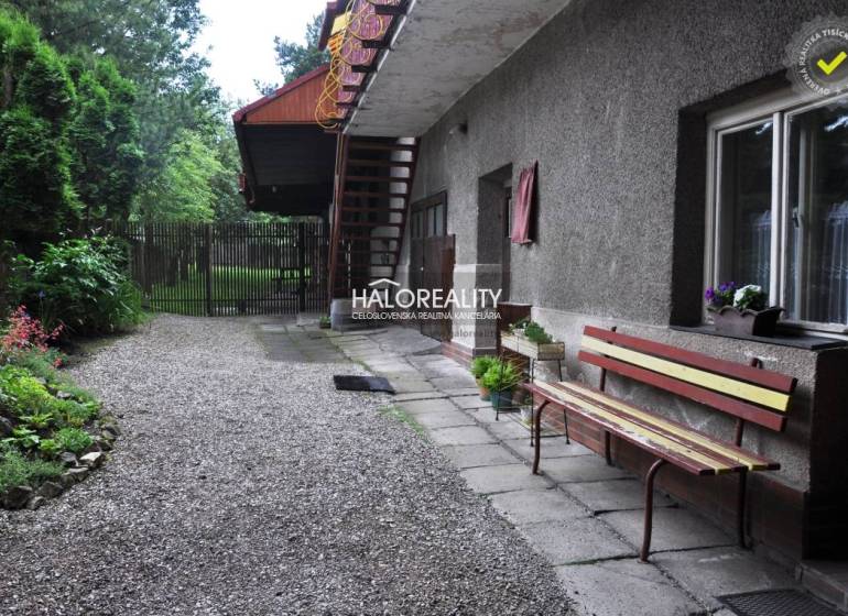 The courtyard of a family house in Nálepkovo with a bench and a garden full of greenery.