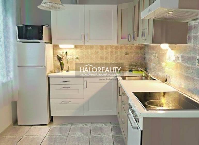 A kitchen in a 3-room apartment with a light-colored kitchen unit, stove, and refrigerator.