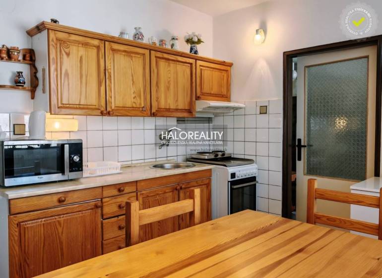 A kitchen in a 3-room apartment with wooden furniture and white tiles above the work surface.