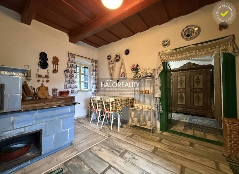 A rustic kitchen in a cottage with a blue stove, decorative plates, and a wooden-patterned floor.