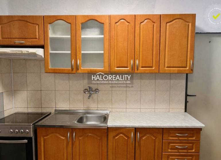 A kitchen with wooden cabinets and a stainless steel sink in a 4-room apartment.
