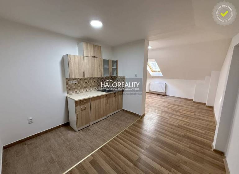 A studio apartment with a wooden floor and a kitchenette.