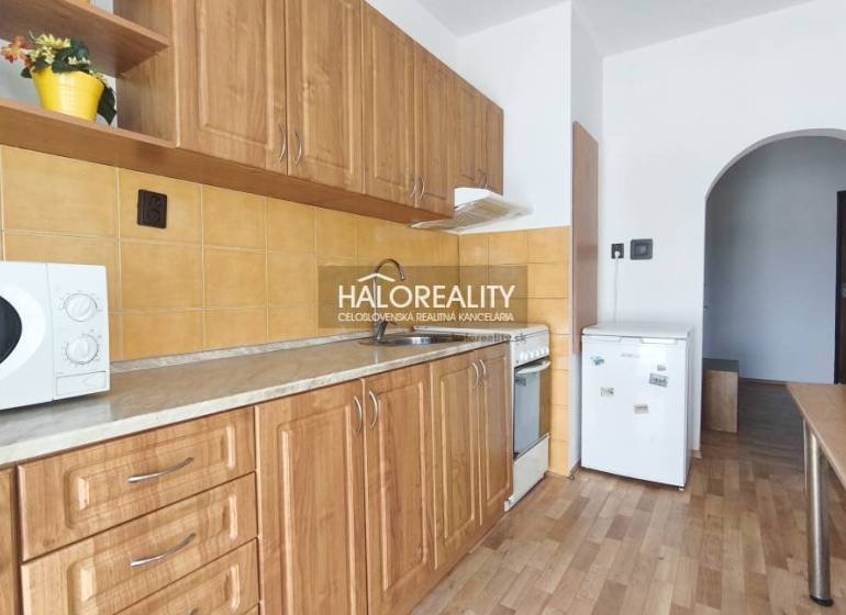 A kitchen in a 3-room apartment with a wooden decor floor and wooden cabinets.