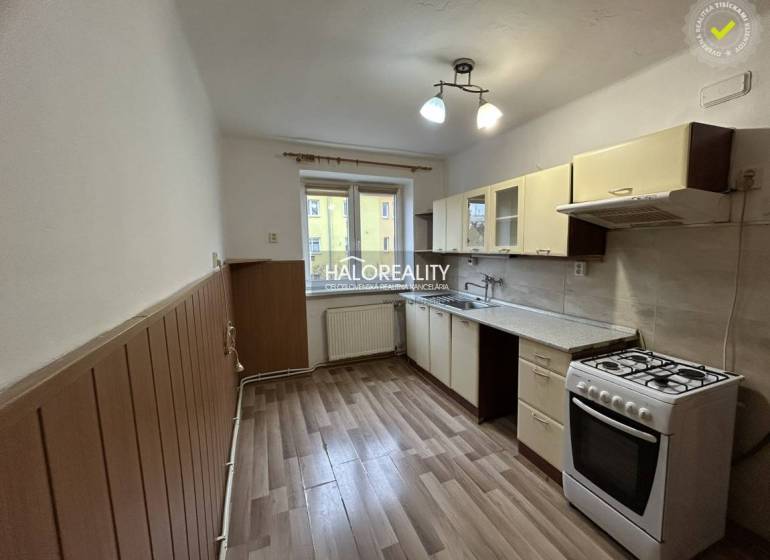 A kitchen in a 2-room apartment with a gas stove and a floor with a wooden decor.
