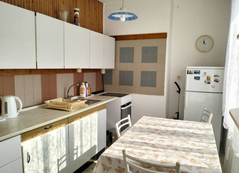 A kitchen in a 2-room apartment with a white kitchen unit and a dining table.