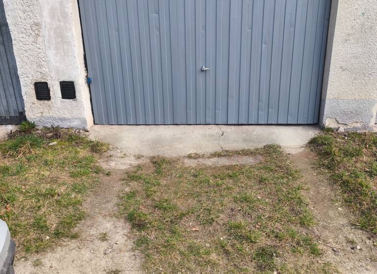 Garages on Kozmonautov Street in Martin with gray metal doors and a grassy edge.
