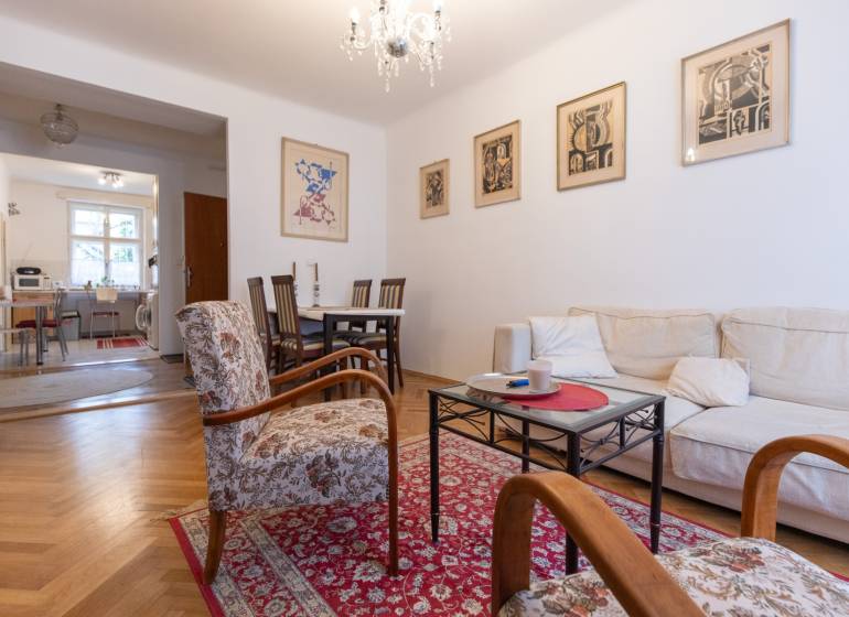 Living room with a sofa, armchairs, and a wooden decor floor in a three-room apartment.