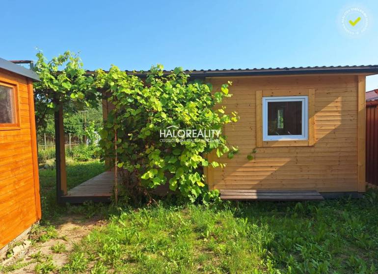 Wooden garden house with a terrace in the Gardens of Bojnice surrounded by greenery.