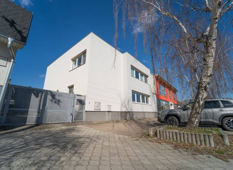 A family house on Bratislavská Street in Pezinok with a paved yard and a silver car.