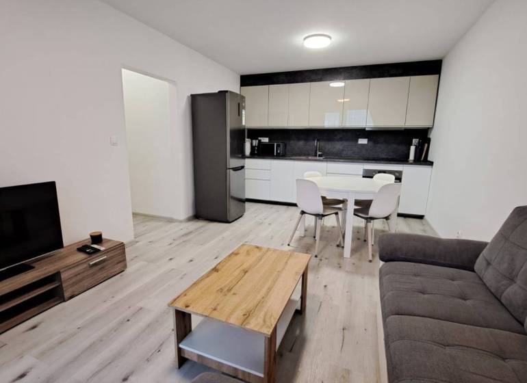 Living room with kitchen in a family house, wooden decor flooring, light furnishings.