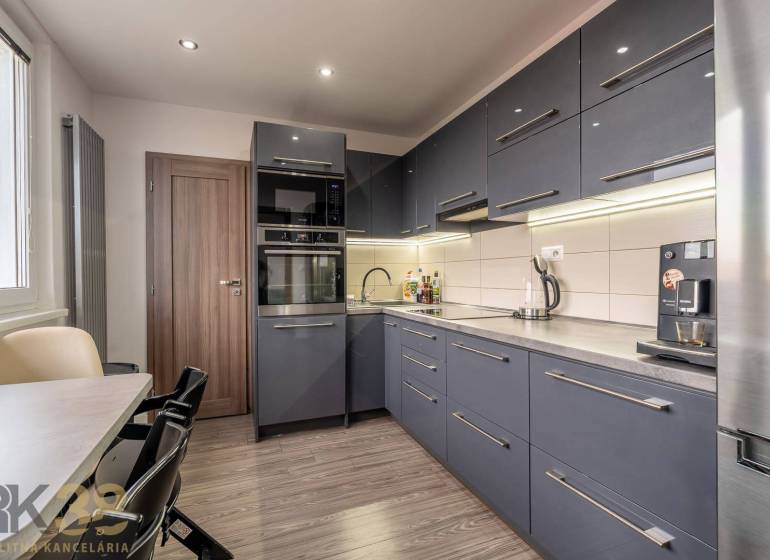 A kitchen in a 4-room apartment with a wood-patterned floor and modern furniture.