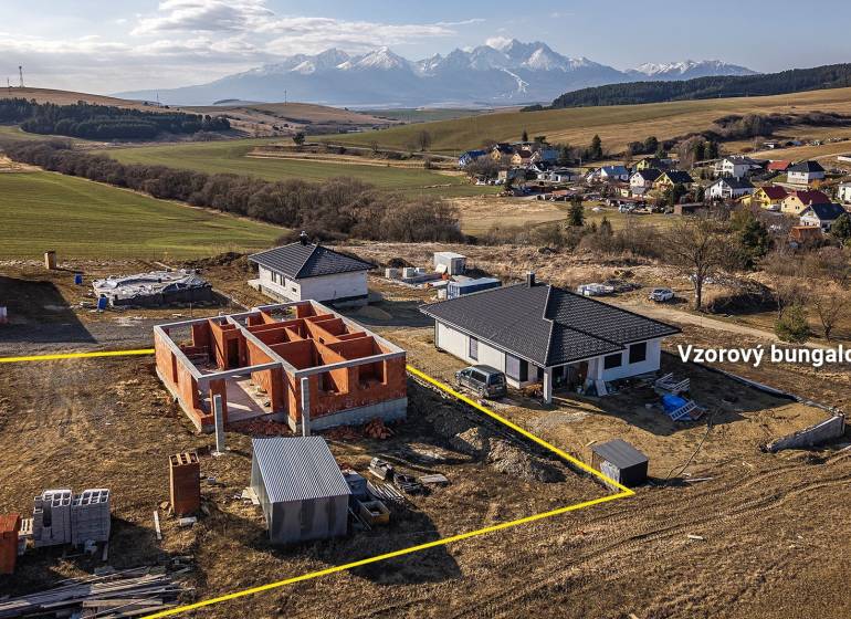 A family house in Tvarožná with construction work in the background of a mountain massif.