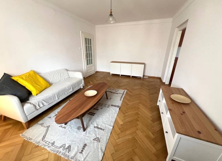 Living room with wood-patterned flooring, a sofa, and a wooden coffee table.