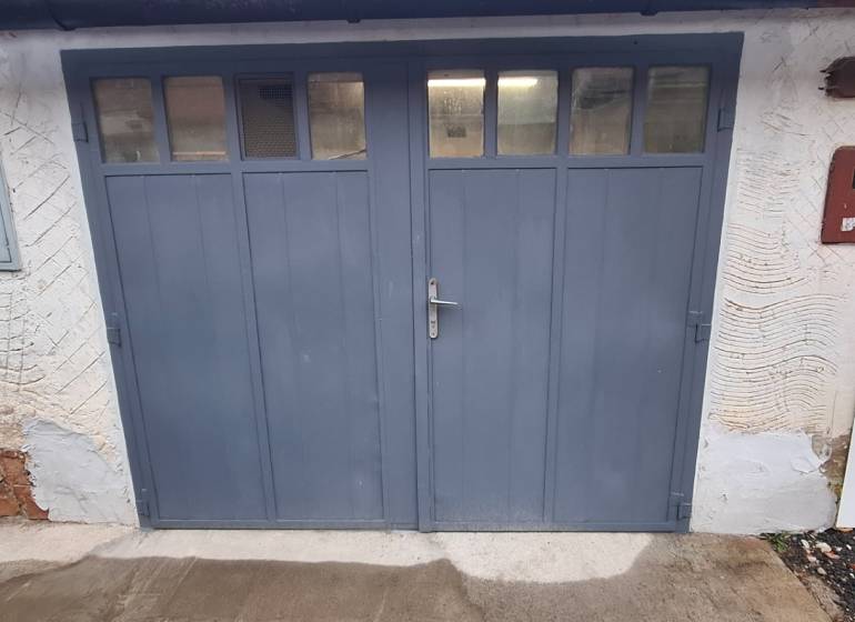 Blue garage doors on Prachatická Street in Zvolen with a white facade.