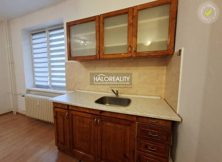 Kitchen unit with a sink and cabinets in a studio apartment with a wooden decor floor.