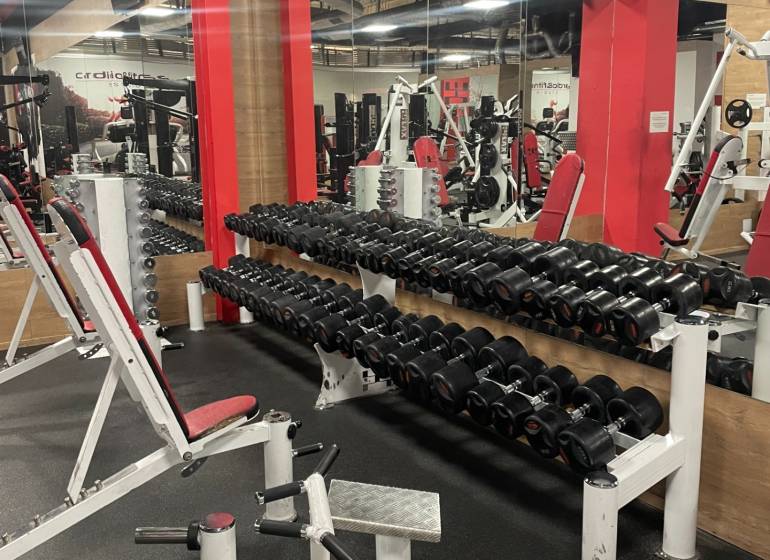Fitness center with dumbbells and exercise equipment, commercial premises.