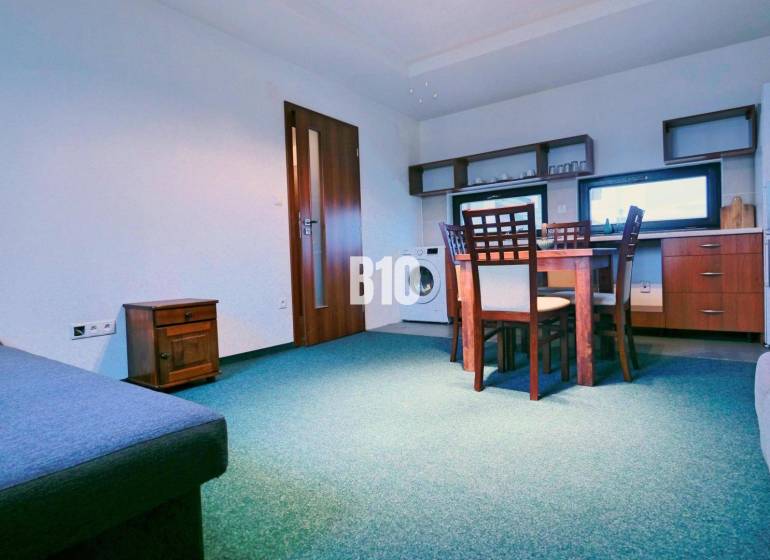 Living room with a sofa, dining table, and kitchenette in a three-room apartment.