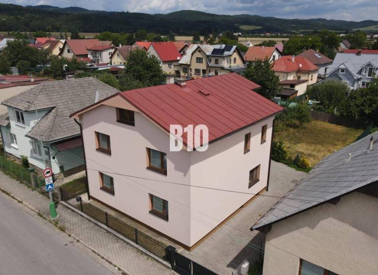 A family house in Bytča with a red roof, surrounded by other houses and nature.