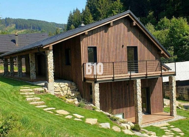 A wooden cottage in Horná Mariková surrounded by greenery and hilly landscape.