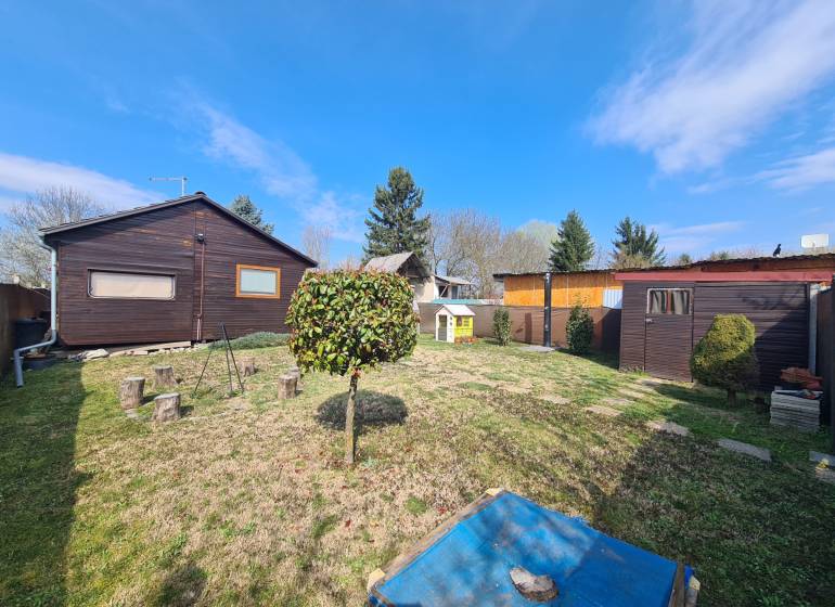 A garden with a wooden cottage in Štúrovo, surrounded by greenery and a manicured lawn.
