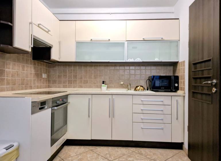 A kitchen in a 3-room apartment with tiles and appliances, cream-colored cabinet doors.