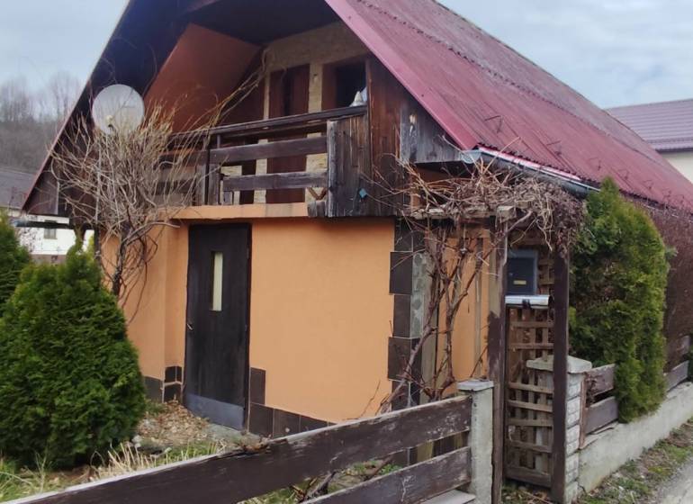 A family house in Horelica in Čadca with a red roof and a wooden fence.