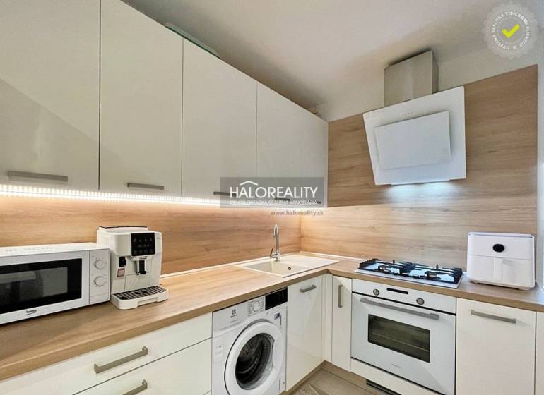 A kitchen in a 2-room apartment with modern appliances and a wooden decor floor.