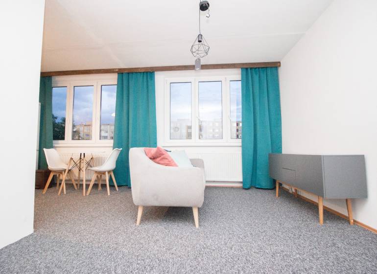 Living room in a 4-room apartment with blue curtains and gray furniture.