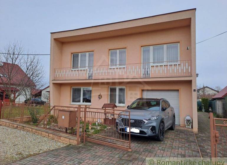 A family house in Veľké Ripňany with a balcony and a car on the driveway.