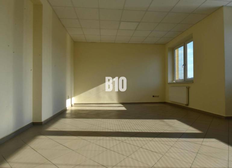 Bright empty room and office with a window and radiator, beige walls.