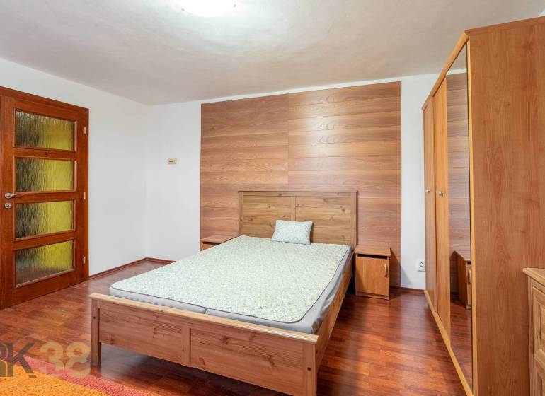 A bedroom in a 5 or more room apartment with a wood-patterned floor, wooden furniture.
