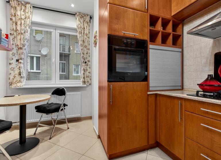 A kitchen in a 3-room apartment with a dining area and wooden cabinet decor.