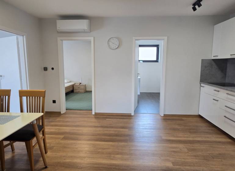 A kitchen in a 3-room apartment with a wooden decor floor and a dining table.