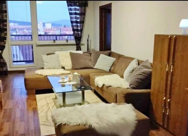 Living room in a three-room apartment with a sofa, glass table, and a view from the window.