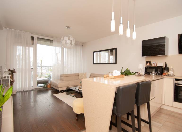 Living room in a two-room apartment with a sofa and wooden decor flooring.