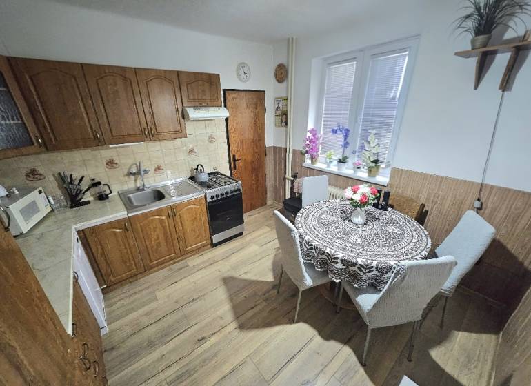 A kitchen in a family house with wooden decor, with a dining table and kitchen unit.