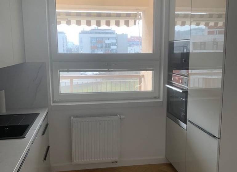 A kitchen with a wooden decor floor in a 2-room apartment has modern appliances.
